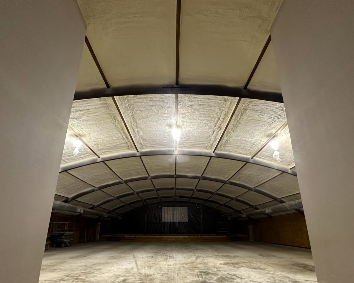 Open-cell spray foam across the arched ceiling of a large metal building